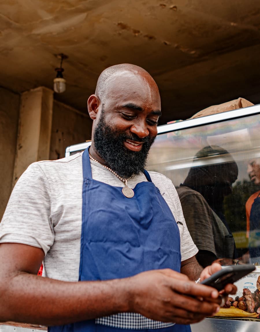 A small business owner smiling while checking an order on their phone
